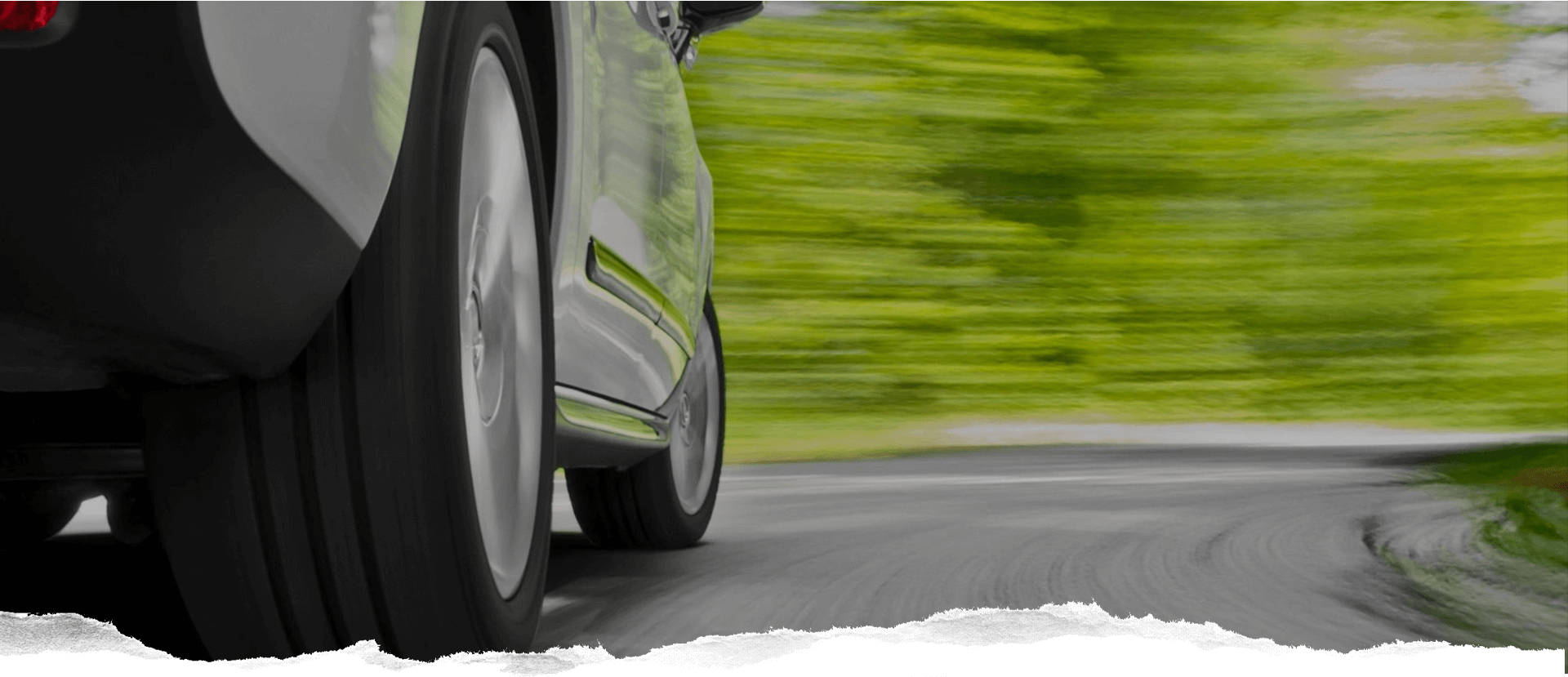 A car driving down the road with trees in the background.